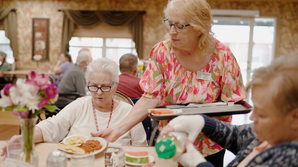 A nurse gives residents dinner at a skilled nursing facility