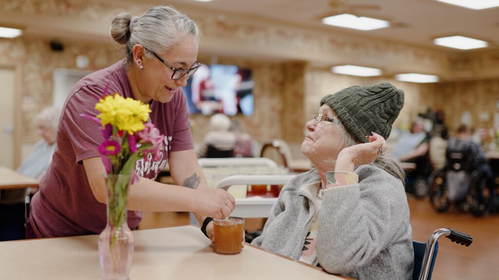 A woman smiles at a nurse at a long term care facility